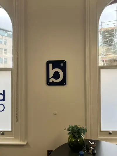 Navy acrylic Bluebird Care bird-logo plaque on a wall between two tall arched windows