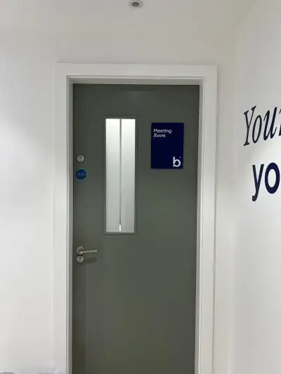 Navy Bluebird Care Meeting Room acrylic door sign beside a grey office door