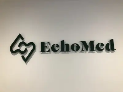 Dark green EchoMed logo and lettering fixed to a white wall