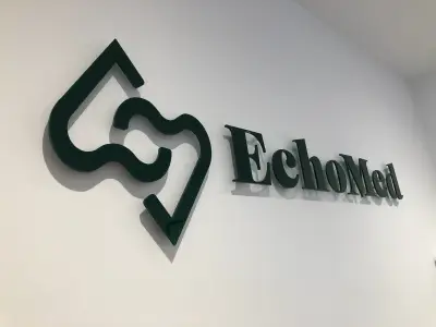 Angled view of dark green built-up EchoMed logo and lettering on a white wall