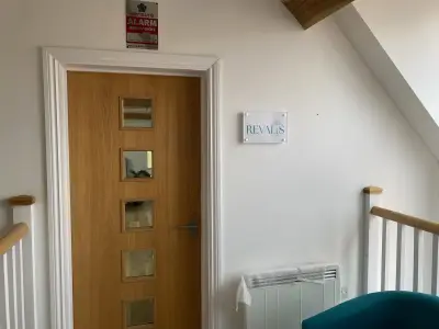 Revalis acrylic logo plaque mounted on a white wall beside an oak office door