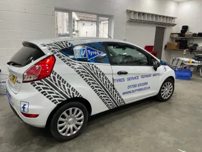 White Ford Fiesta van with tyre-tread graphics and 2U Tyres part wrap, rear side view