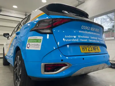 Bluebird Care blue Kia Sportage, full wrap, rear offside close-up listing service-area towns