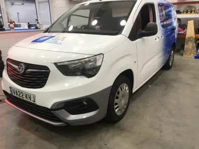 White Vauxhall Combo van, DJK Electrical part wrap, front end inside workshop