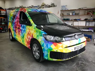 Floral Image rainbow VW Caddy van, full wrap, front-side view inside workshop