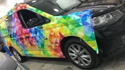 Rainbow-geometric VW Caddy van, Floral Image full wrap, close side view during fitting