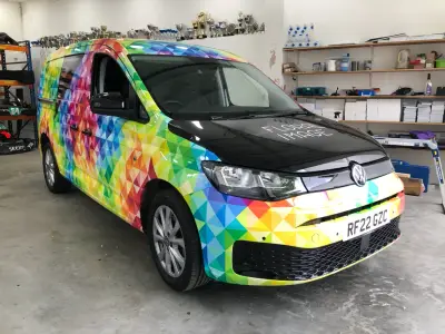Floral Image rainbow VW Caddy van, full wrap, nearside front three-quarter inside workshop
