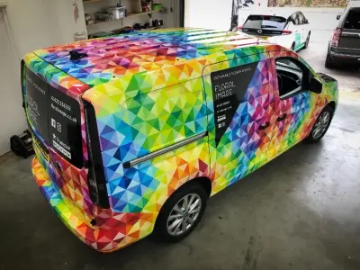 Rear angle of Floral Image VW Caddy van in rainbow triangle full wrap, in workshop