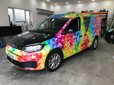 Front three-quarter of Floral Image VW Caddy van, black bonnet and rainbow geometric full wrap