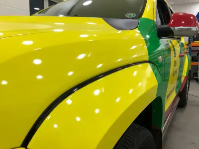 Close-up of wheel-arch join on yellow and green Green Label PHEM pickup wrap
