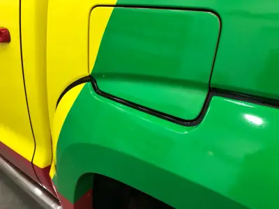 Close-up of fuel-cap area on yellow and green wrapped pickup, showing wrap seam detail
