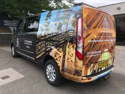 Offside rear of Green Oak Carpentry Ford Transit Custom van with timber-frame photo wrap