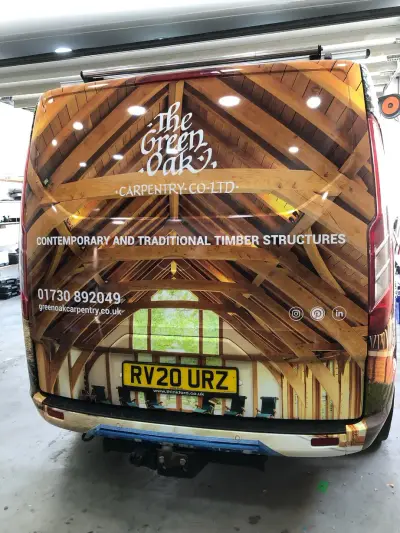 Rear doors of Green Oak Carpentry van wrapped with oak-roof timber-frame photograph and logo