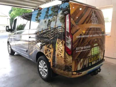 Rear three-quarter of Green Oak Carpentry Ford Transit Custom with timber-frame photo wrap