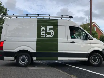 Side of white VW Crafter van with green Lock5 stripe and large logo part wrap