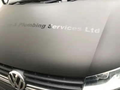 Front of matte grey VW van with NB Heating & Plumbing Services Ltd bonnet signwriting