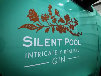 Close-up of Silent Pool Gin logo and copper floral graphic on a turquoise van wrap