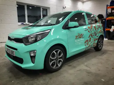 Turquoise Kia Picanto fully wrapped with Silent Pool Gin floral graphics, front quarter