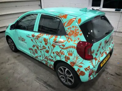 Close-up of copper crown and botanical graphics on a turquoise Silent Pool Gin car wrap