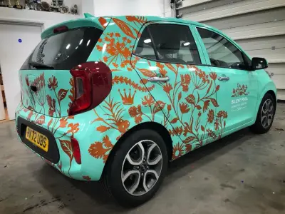 Turquoise Kia Picanto wrapped in Silent Pool Gin copper floral graphics, rear quarter