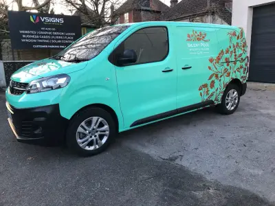Turquoise Silent Pool Gin Vauxhall Vivaro van beside the V Signs shopfront pavement sign, front quarter