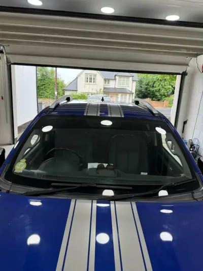 Front of blue Isuzu D-Max pickup with silver twin racing stripes over bonnet and roof