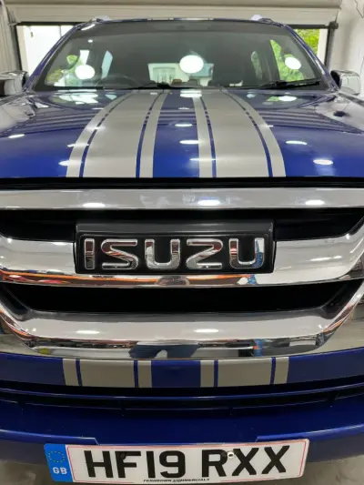 Silver racing-stripe detail over the bonnet and Isuzu grille of a blue D-Max pickup