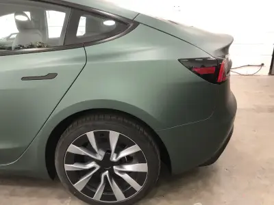 Rear quarter of a Tesla Model S wrapped in matt metallic pine green colour-change vinyl