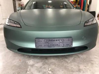 Front close-up of a Tesla Model S in a matt metallic pine green full wrap in the workshop