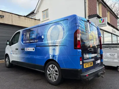 DJK Electrical blue van with lightbulb graphic wrap outside VSIGNS shop, rear quarter