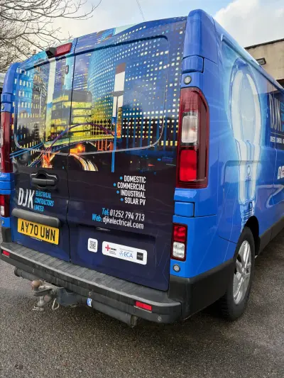 Rear of blue DJK Electrical Contractors van with lit skyline and lightbulb full wrap by V Signs