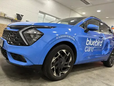 Bright blue Kia Ceed with full vehicle wrap featuring 'bluebird care' branding and 'It's good to be home' tagline