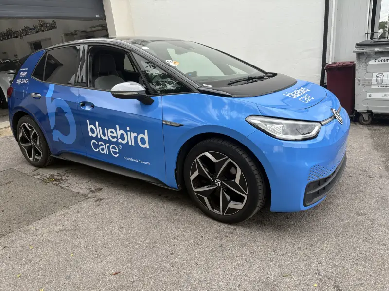 Volkswagen ID.3 electric car in Bluebird Care's current branding — rich blue with the modern 'b' bird logo and wave pattern, front three-quarter view