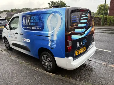 Rear of DJK Electrical Contractors compact van with lightbulb and city skyline wrap