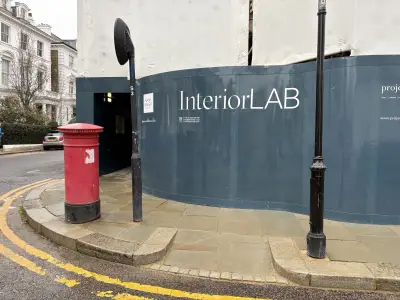 Construction hoarding panels with white InteriorLAB and Nash Baker branding on dark teal, London street corner