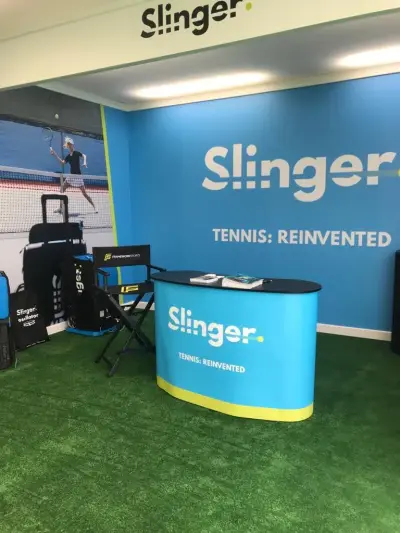 Slinger tennis event stand with blue 'Tennis: Reinvented' wall graphics and printed branded counter