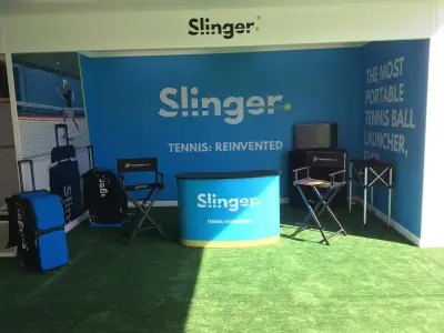 Slinger tennis stand with blue 'Tennis: Reinvented' wall graphics, branded counter and directors chairs