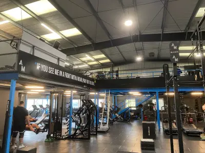 Two-tier gym with printed motivational quote fascia panels and AM branding on blue mezzanine