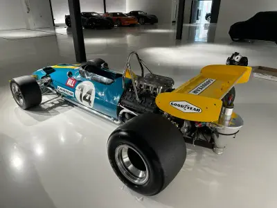 Teal and yellow classic F1 car number 14 with yellow rear wing and Goodyear decals, side-rear view