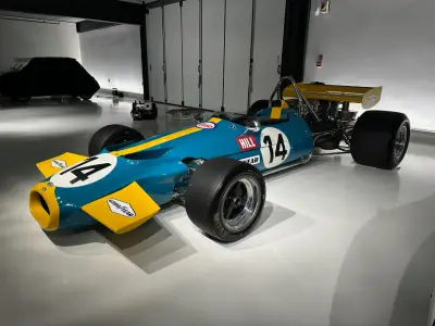 Teal and yellow vintage F1 single-seater number 14 with Goodyear decals, front three-quarter view