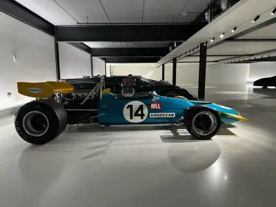 Full side profile of teal and yellow vintage F1 car number 14 with yellow rear wing in showroom