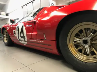 Red Ford GT40 race car flank with black 24 roundel, 'P' and Alan Mann Racing decals, gold wheels