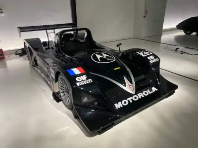 Black Motorola-liveried Lola LMP sports-prototype number 25, front three-quarter view in showroom