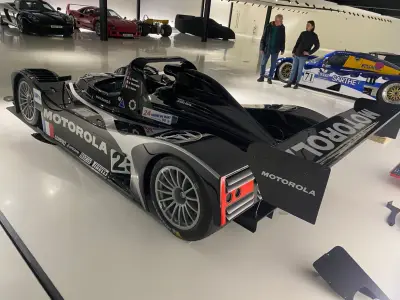 Black Motorola Lola LMP1 prototype number 25, rear-quarter view showing Judd engine, in showroom