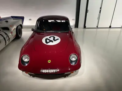Front view of maroon Lotus Elan 26R race coupe with black 42 roundel and Lotus badge, plate 484 UXY
