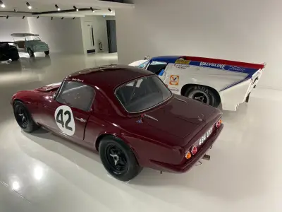 Maroon Lotus Elan 26R coupe number 42, rear-side view with 484 UXY plate in showroom