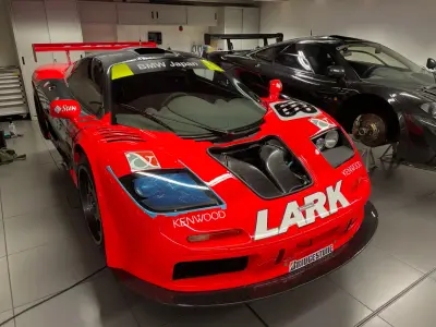 Red Lark-liveried McLaren F1 GTR front three-quarter in workshop, Kenwood and Bridgestone decals