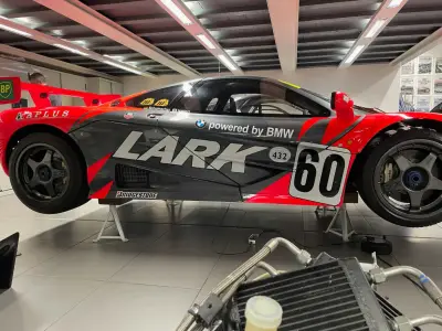 Grey and red Lark McLaren F1 GTR side profile on stands, powered by BMW livery