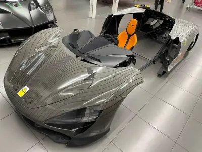 Silver pinstripe-wrapped McLaren Speedtail body sections and orange seat in showroom