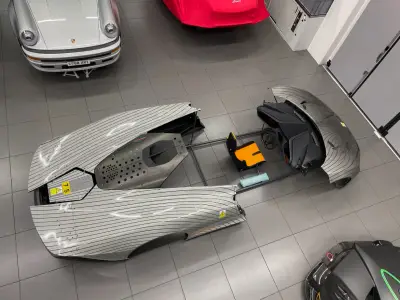 Overhead view of disassembled silver pinstripe-wrapped McLaren Speedtail on showroom floor